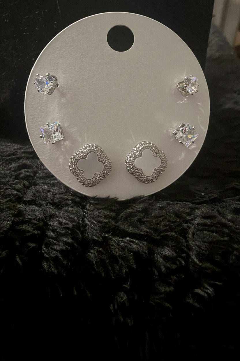 Clover & Stud Set featuring silver-tone metal clover-shaped earrings and clear crystal stud earrings on a white holder.