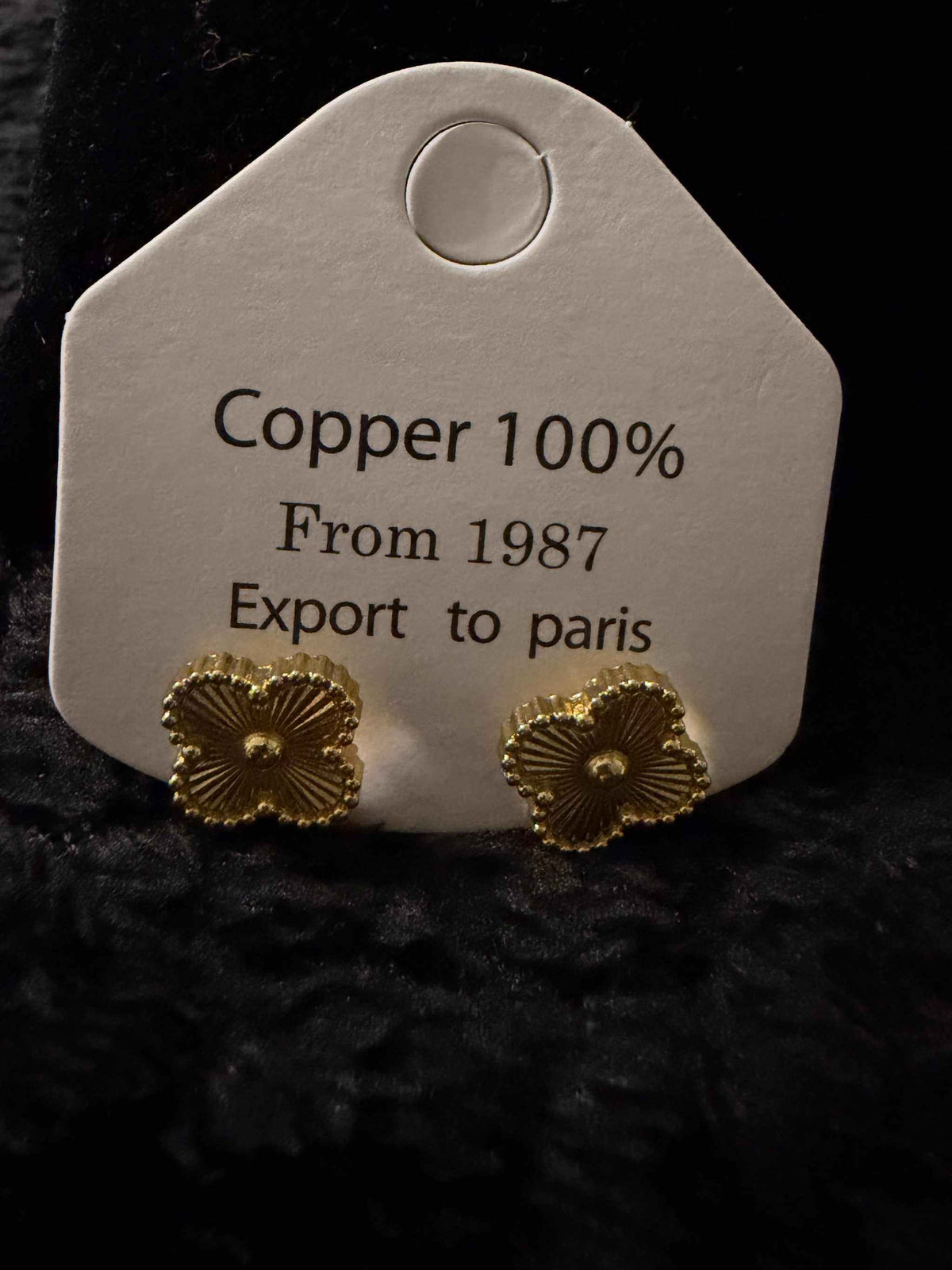 Gold Clovers Earrings in gold-tone copper with textured four-leaf clover design on a display card labeled Copper 100%