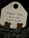 Bronze Clover Earrings styled as dark brown copper clover-shaped studs with beaded edges on a white card.
